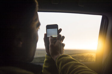 Man taking photo of sunset through the window, Hofn, East Iceland, Iceland - AURF07887