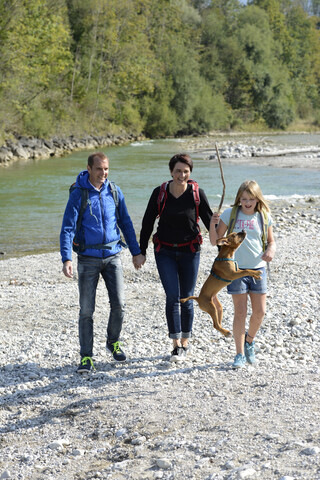 Family hiking with backpacks and a dog at the river Isar, Upper Bavaria, Germany stock photo