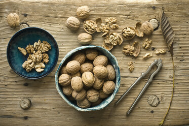 Whole and cracked walnuts in bowls on wood - ASF06255