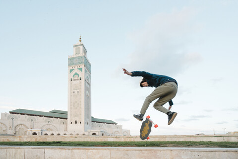 Side view of man skateboarding against Mosque Hassan II stock photo