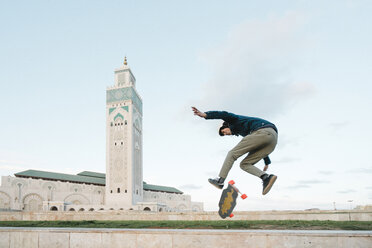 Side view of man skateboarding against Mosque Hassan II - CAVF54973