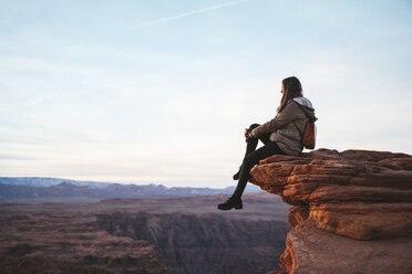 Seitenansicht einer auf einem Felsen sitzenden Frau bei der Horseshoe Bend gegen den Himmel - CAVF54981