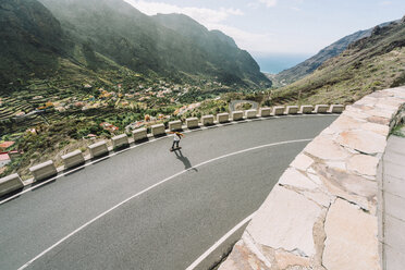 High angle view of man skateboarding on mountain road during sunny day - CAVF54984