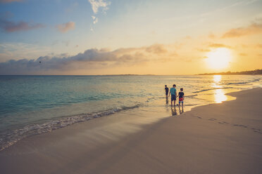 Geschwister stehen am Strand gegen den Himmel bei Sonnenuntergang - CAVF54993