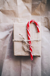 Candy cane tied up with Christmas present on brown paper - CAVF55005