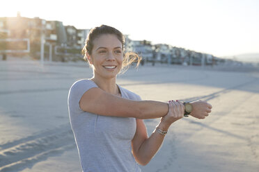 Lächelnde Frau mit ausgestrecktem Arm an einem sonnigen Tag am Strand - CAVF55011