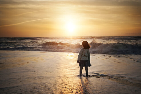Rückansicht eines am Strand stehenden Mädchens gegen den Himmel bei Sonnenuntergang - CAVF55021