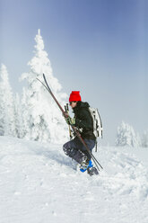 Seitenansicht eines Wanderers mit Rucksack und Ski auf einem verschneiten Hügel im Winter - CAVF55046