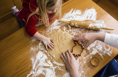 Hohe Winkel Ansicht des Mädchens Blick auf Vater macht Cookies auf Holztisch zu Hause - CAVF55053