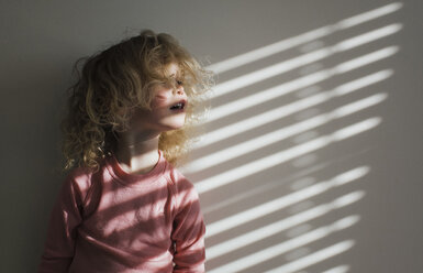 Girl looking away while standing against wall at home - CAVF55054