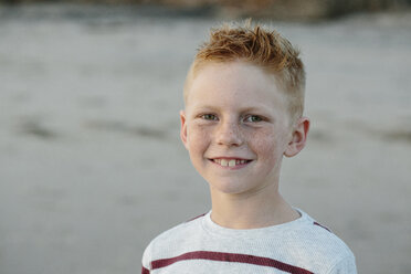 Porträt eines lächelnden Jungen mit Sommersprossen am Strand - CAVF55087