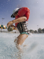 Seitenansicht eines verspielten Mädchens, das sich im Sommer im Schwimmbad vergnügt - CAVF55088