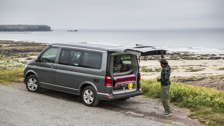 Seitenansicht eines Mannes, der an einem Wohnmobil am Strand steht, gegen den Himmel - CAVF55099