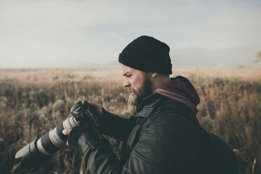 Side view of hiker looking at camera while standing on field - CAVF55183