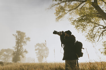Niedriger Blickwinkel eines Wanderers, der mit seiner Kamera auf einem Feld steht und fotografiert - CAVF55184