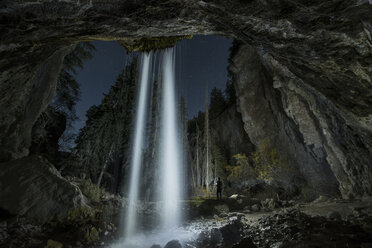 Rückansicht der Silhouette Mann stehend durch Wasserfall im Wald bei Nacht - CAVF55239