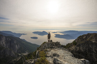 Carefree hiker with backpack looking at view while standing on mountain against sky - CAVF55260