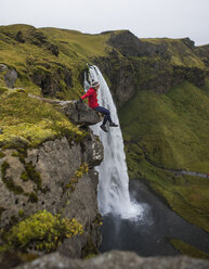 Side view of hiker sitting on rock against waterfall - CAVF55309