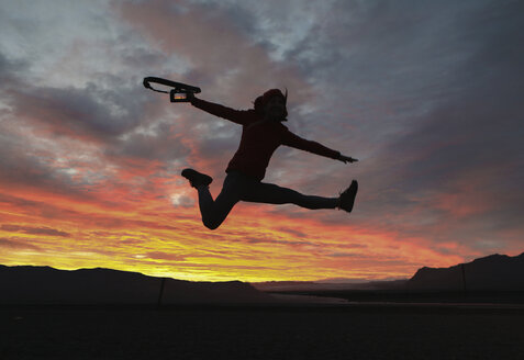 Aufgeregter Wanderer hält die Kamera, während er gegen den dramatischen Himmel springt - CAVF55310