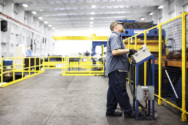 Full length of worker using control machine while working at Steel Industry Factory - CAVF55394