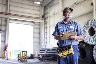 Manual worker holding clipboard while working in metal Steel Industry Factory - CAVF55413