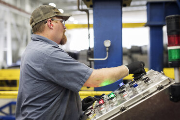 Side view of manual worker using control panels while working in metal Steel Mill - CAVF55423