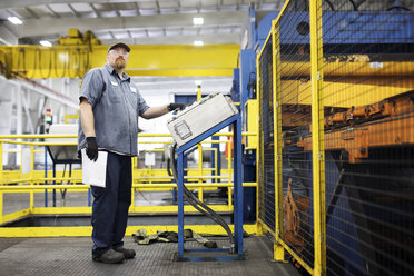 Full length of worker using machine while working in metal Steel Mill - CAVF55426