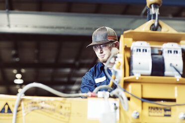 Ernster junger Arbeiter an einer Maschine in der Stahlindustrie - CAVF55434