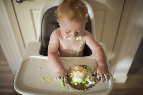 Hohe Winkel Ansicht der Baby-Junge isst Kuchen beim Sitzen auf Hochstuhl zu Hause während Geburtstag - CAVF55452