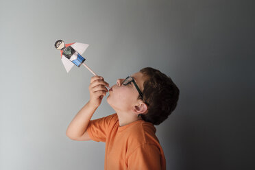 Seitenansicht eines Jungen, der mit einem Superhelden-Spielzeug an der Wand zu Hause spielt - CAVF55456