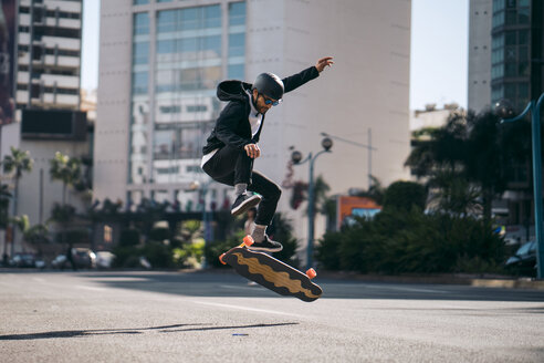 Mann führt Stunt in voller Länge beim Skateboardfahren auf der Straße in der Stadt aus - CAVF55491