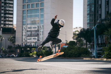 Mann vollführt Stunt beim Skateboardfahren auf der Straße in der Stadt - CAVF55492