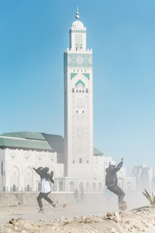 In voller Länge von Freunden beim Skateboarden vor der Moschee Hassan II, lizenzfreies Stockfoto