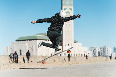 Mann vollführt Stunt beim Skateboardfahren vor der Moschee Hassan II - CAVF55494