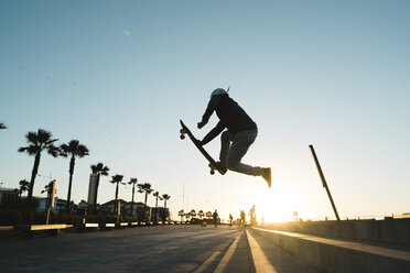 Seitenansicht eines Mannes, der einen Stunt mit dem Skateboard auf der Straße gegen den Himmel macht - CAVF55496