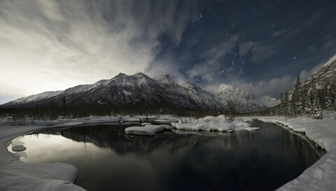 Ruhiger Blick auf den See und die schneebedeckten Berge im Chugach State Park bei Nacht, lizenzfreies Stockfoto