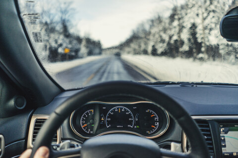 Cropped fingers of man driving car on road during winter stock photo