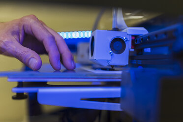 Abgeschnittene Hand eines Ingenieurs, der einen 3D-Drucker im Büro untersucht - CAVF55534