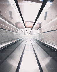 Ansicht einer Rolltreppe mit niedrigem Winkel, die sich auf Glas spiegelt - CAVF55544