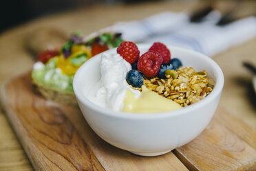 Close-up of breakfast served in bowl on wooden cutting board - CAVF55581