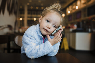 Nahaufnahme eines Mädchens, das ein Mobiltelefon benutzt, während es am Tisch im Restaurant sitzt - CAVF55596