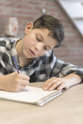 Boy coloring on spiral notebook at table - CAVF55605