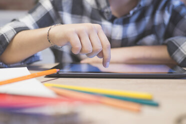 Abgeschnittene Hand eines Jungen, der auf einem Tablet-Computer am Tisch zeichnet - CAVF55608