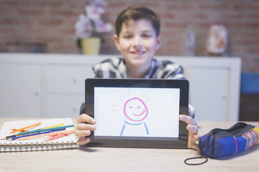 Portrait of smiling boy showing drawing on tablet computer at home - CAVF55609