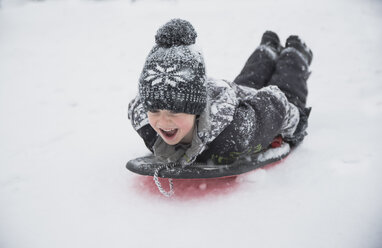 Fröhlicher Junge beim Schlittenfahren im Schnee - CAVF55648