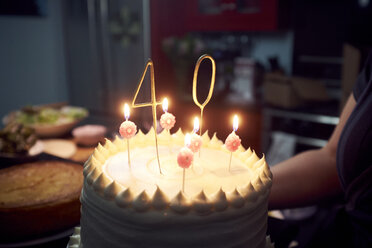 Midsection of woman holding birthday cake at home - CAVF55665