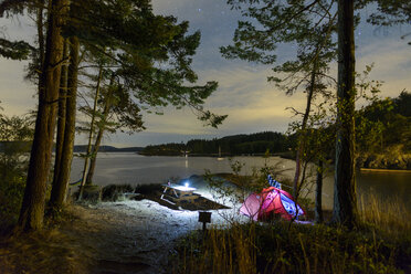 Illuminated tent by lake in forest during dusk - CAVF55672