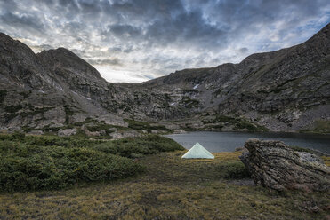 Tent on field at lakeshore against cloudy sky - CAVF55706