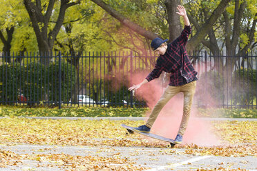 Jugendlicher mit Puderfarbe beim Skateboardfahren auf dem Fußweg im Park im Herbst - CAVF55712