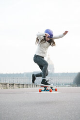 Frau springt in voller Länge beim Skateboardfahren gegen das Musee de larmee - CAVF55762